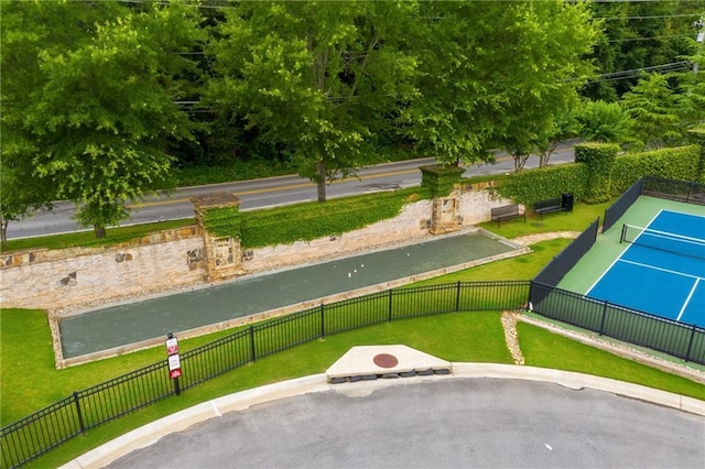 view of community with a tennis court, fence, and a yard