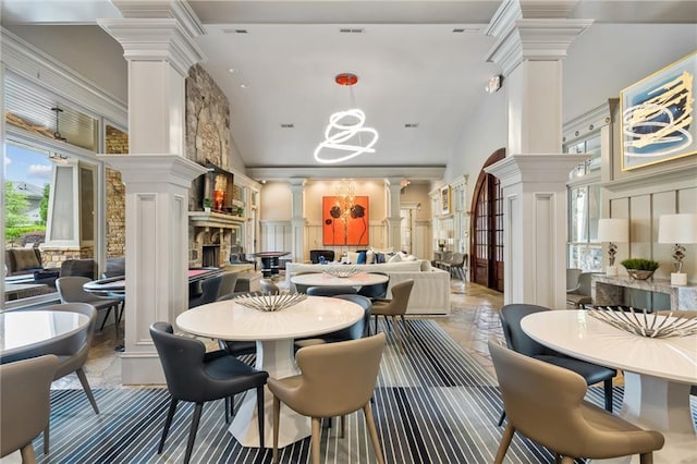 dining space with ornate columns, high vaulted ceiling, a decorative wall, and a chandelier