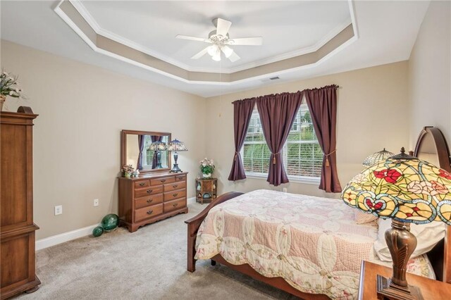 carpeted bedroom with ceiling fan, a raised ceiling, and ornamental molding