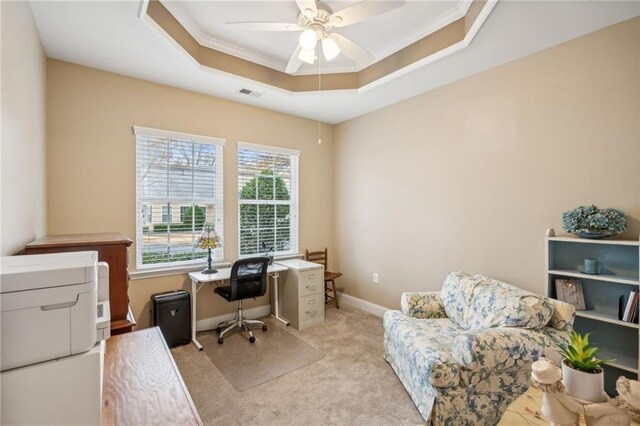 office featuring ceiling fan, light colored carpet, crown molding, and a tray ceiling