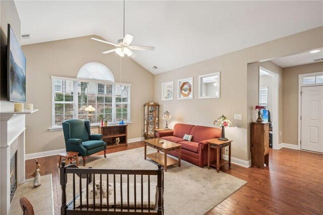 living room with lofted ceiling, ceiling fan, and wood-type flooring