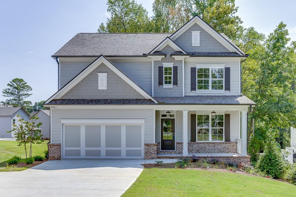 craftsman house with covered porch, a garage, and a front lawn