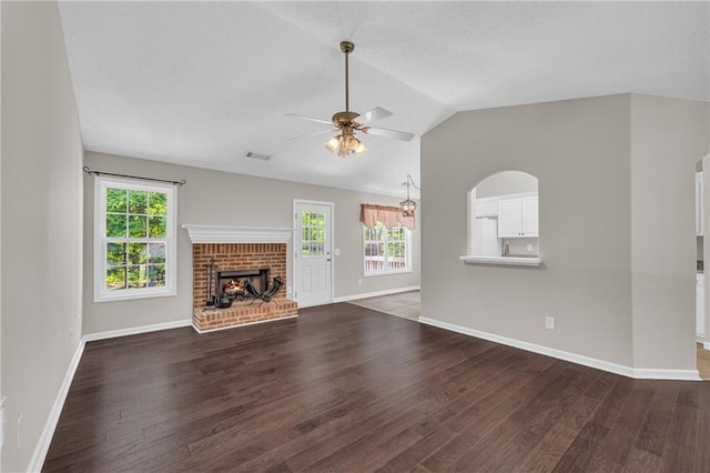 unfurnished living room featuring dark wood-style floors, ceiling fan, lofted ceiling, baseboards, and a brick fireplace