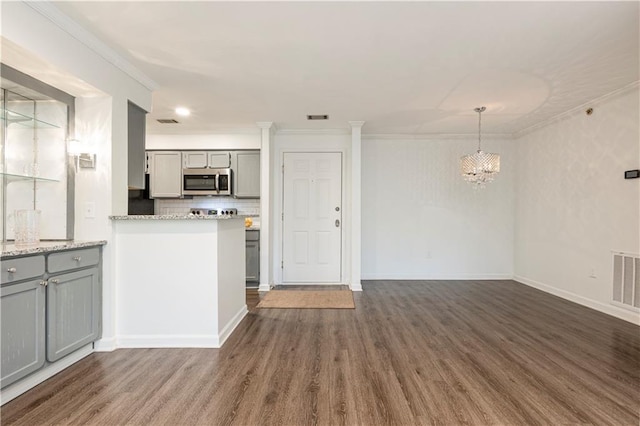 kitchen featuring backsplash, ornamental molding, decorative light fixtures, gray cabinets, and dark hardwood / wood-style floors