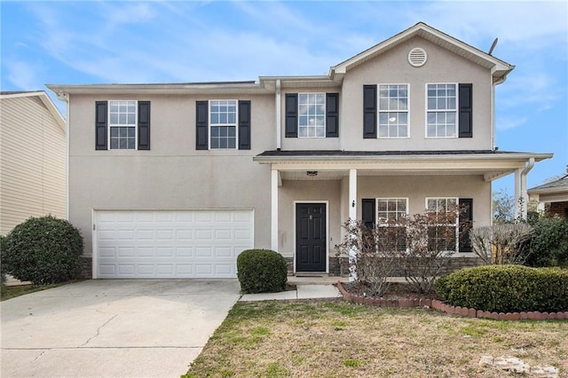 view of front facade with an attached garage, covered porch, concrete driveway, and stucco siding