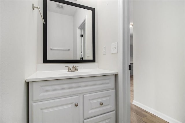 bathroom featuring visible vents, baseboards, wood finished floors, and vanity