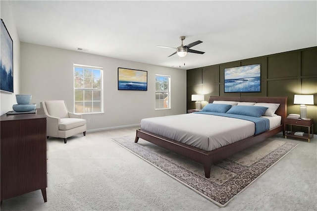 bedroom featuring baseboards, light colored carpet, visible vents, and a ceiling fan