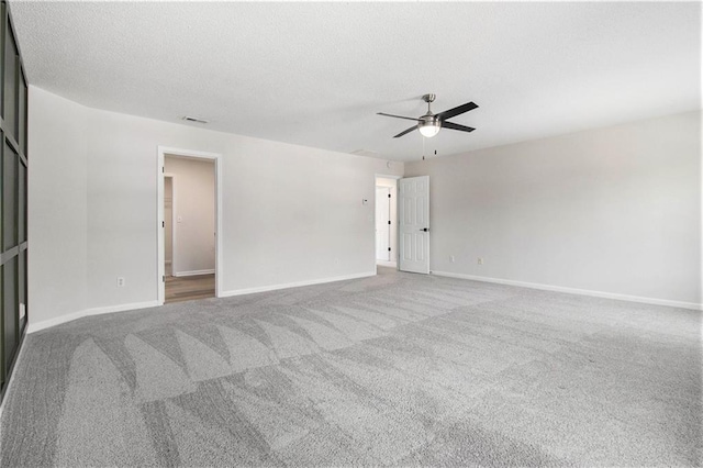 unfurnished room featuring carpet, a textured ceiling, visible vents, and a ceiling fan