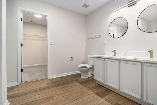 bathroom featuring toilet, wood finished floors, a sink, and visible vents