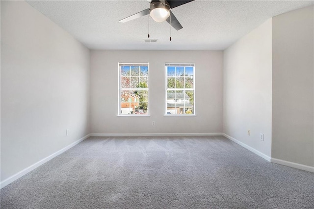 empty room featuring a textured ceiling, carpet floors, a ceiling fan, visible vents, and baseboards