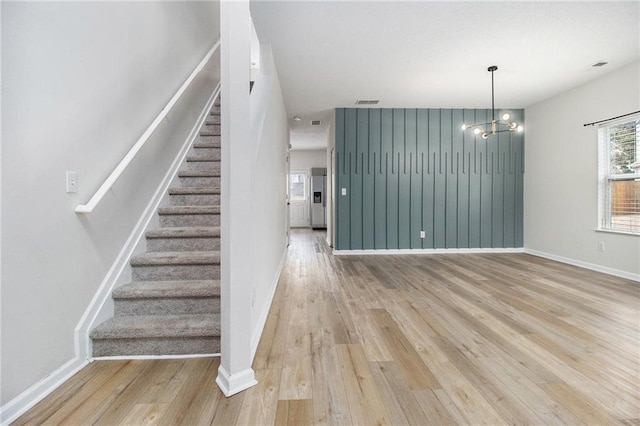 interior space featuring visible vents, baseboards, stairs, light wood-style floors, and a notable chandelier