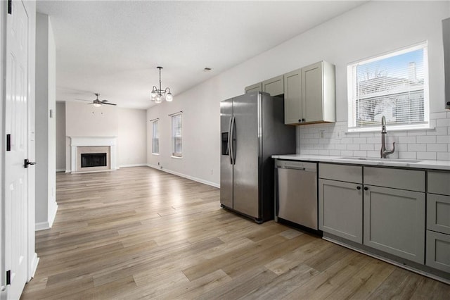 kitchen featuring stainless steel appliances, a wealth of natural light, tasteful backsplash, gray cabinetry, and a sink