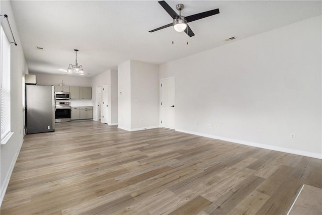 unfurnished living room featuring ceiling fan with notable chandelier, light wood-type flooring, visible vents, and baseboards