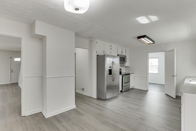 kitchen with visible vents, stainless steel appliances, light countertops, light wood-style floors, and white cabinetry