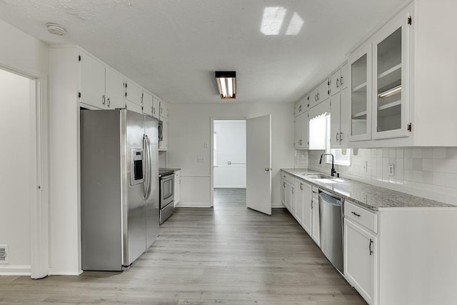 kitchen featuring decorative backsplash, light wood-style flooring, appliances with stainless steel finishes, and a sink