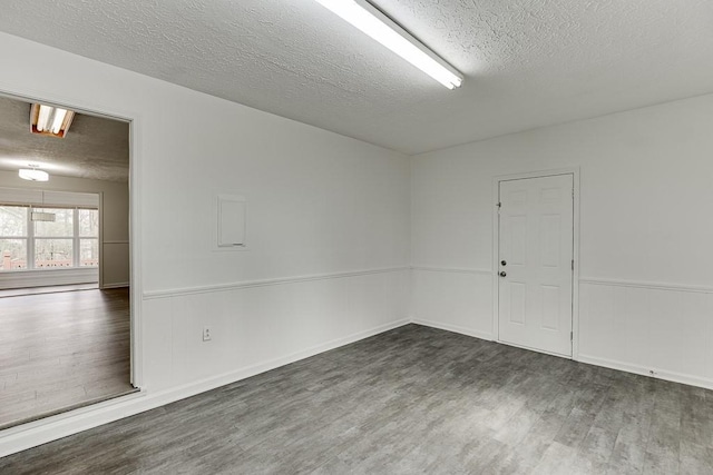 unfurnished room with a wainscoted wall, a textured ceiling, and wood finished floors