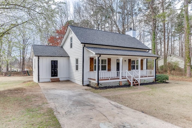 view of front facade featuring a porch, a chimney, a shingled roof, concrete driveway, and board and batten siding