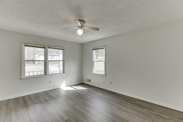 empty room with visible vents, baseboards, dark wood finished floors, ceiling fan, and a textured ceiling