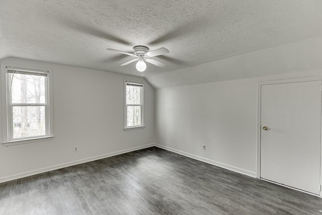 empty room featuring dark wood-style floors, baseboards, ceiling fan, and vaulted ceiling