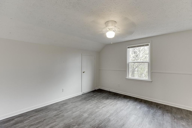 empty room with a ceiling fan, a textured ceiling, wood finished floors, baseboards, and vaulted ceiling