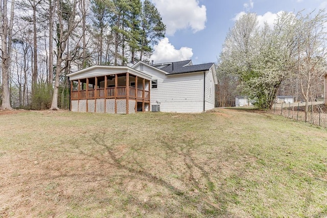 rear view of property featuring a porch, a yard, central AC, and fence