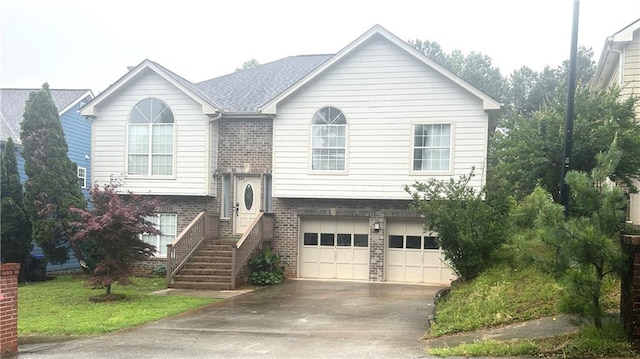 bi-level home featuring brick siding, a garage, and concrete driveway
