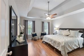 bedroom featuring a raised ceiling, wood finished floors, and a ceiling fan