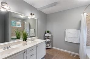 bathroom with a shower with shower curtain, double vanity, a tub to relax in, and baseboards
