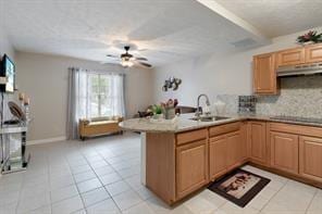kitchen with a sink, a peninsula, black cooktop, and light tile patterned floors