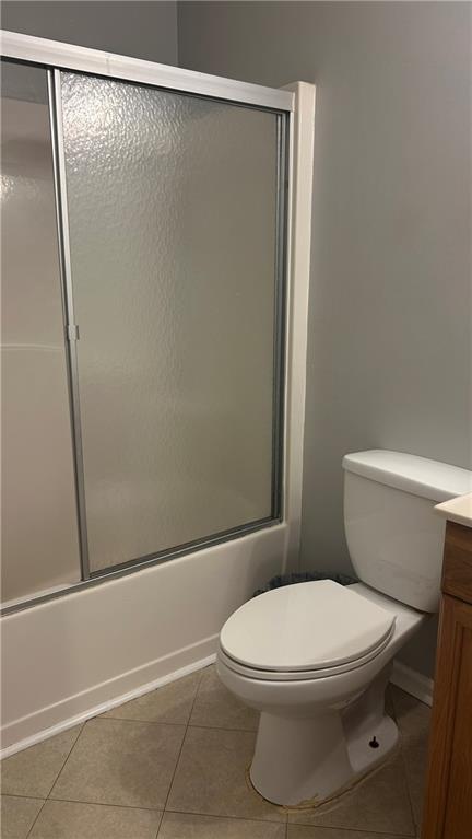 full bathroom with tile patterned flooring, bath / shower combo with glass door, vanity, and toilet