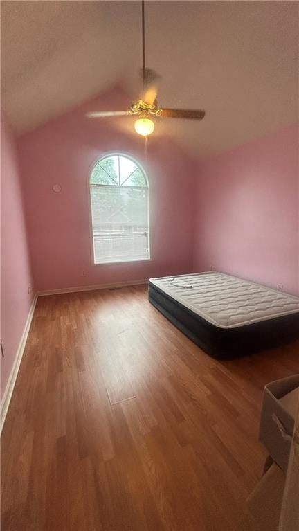 unfurnished bedroom featuring wood finished floors, vaulted ceiling, ceiling fan, and baseboards