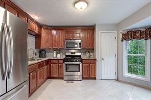 kitchen with appliances with stainless steel finishes, light countertops, brown cabinets, and a sink