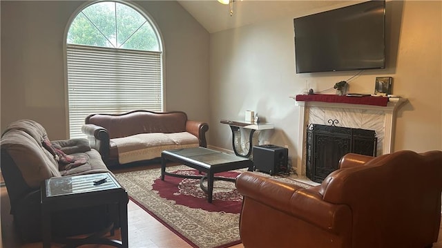 living area with vaulted ceiling, wood finished floors, and a premium fireplace