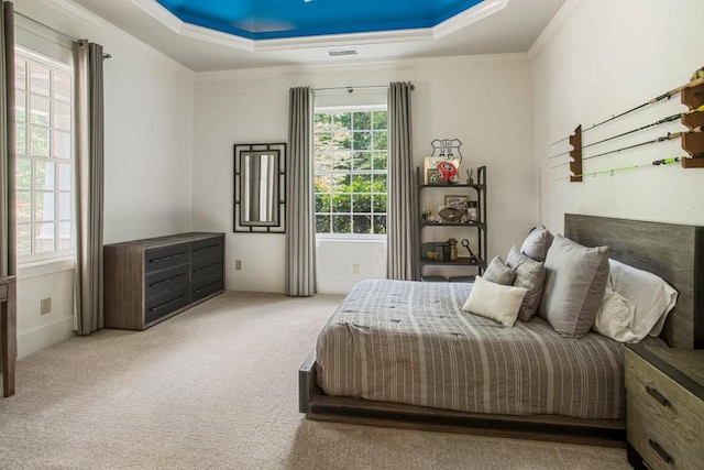 bedroom with crown molding, light carpet, and a tray ceiling