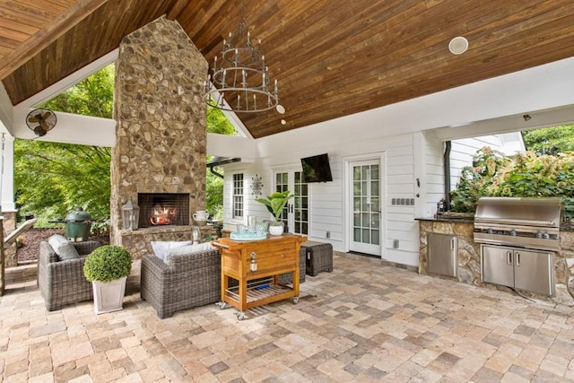 view of patio / terrace featuring a grill, exterior kitchen, and an outdoor stone fireplace