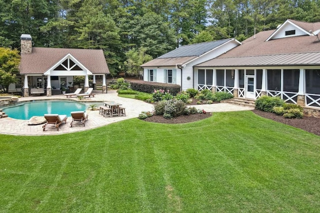 rear view of property with a lawn, a sunroom, and a patio