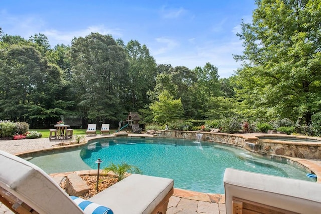 view of pool with pool water feature, a patio, a playground, and an in ground hot tub