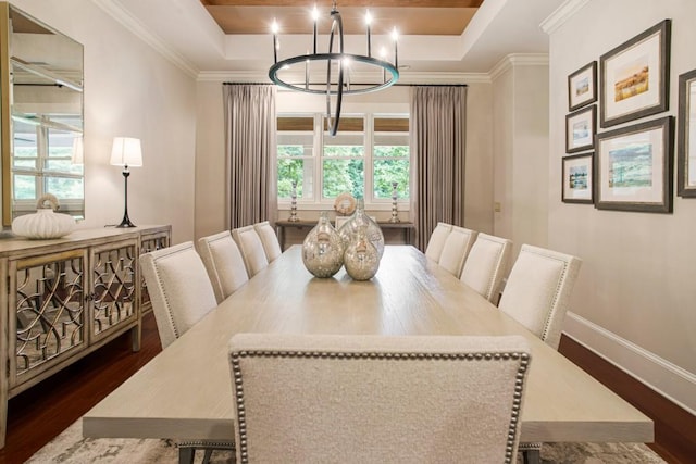 dining room featuring an inviting chandelier, ornamental molding, a tray ceiling, and dark wood-type flooring