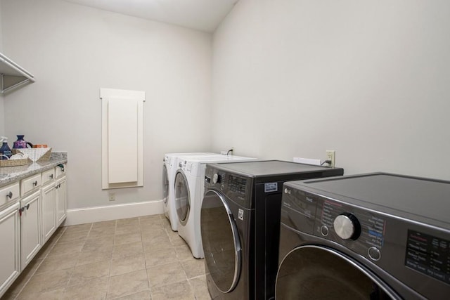 washroom featuring cabinets, washing machine and dryer, and light tile patterned floors