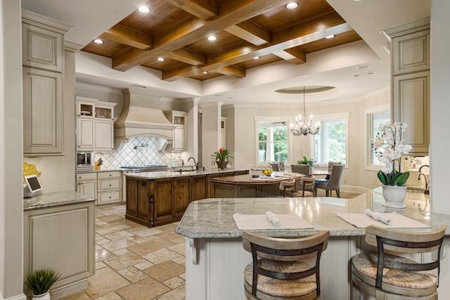 kitchen featuring custom exhaust hood, light stone counters, and cream cabinetry