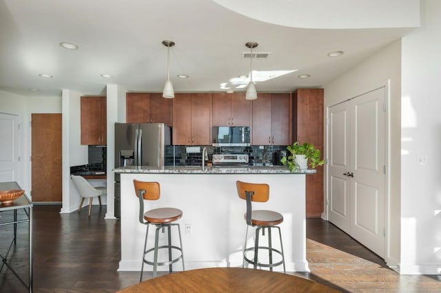 kitchen with visible vents, a breakfast bar, appliances with stainless steel finishes, decorative backsplash, and dark wood-style flooring