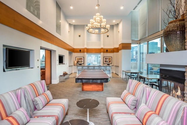 playroom featuring a multi sided fireplace, carpet, a high ceiling, baseboards, and a chandelier