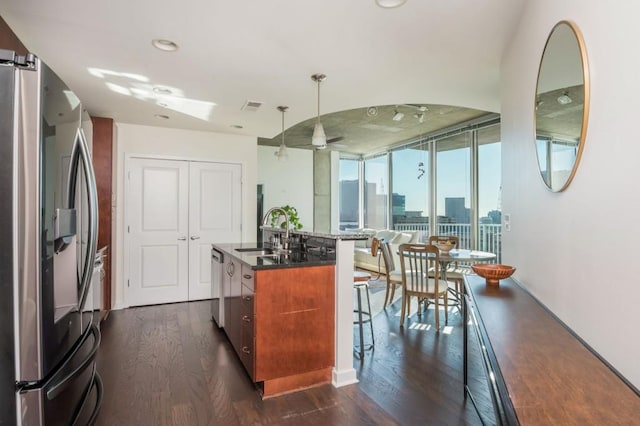 kitchen featuring dark wood finished floors, a sink, appliances with stainless steel finishes, a city view, and a kitchen breakfast bar