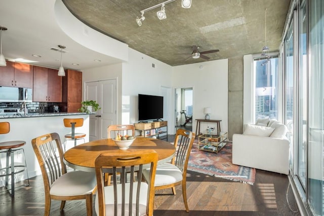 dining area with a ceiling fan, dark wood-type flooring, a healthy amount of sunlight, and track lighting