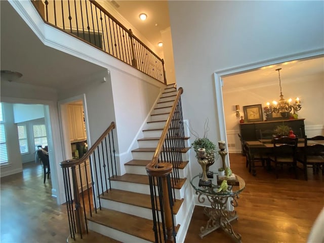 stairs with a high ceiling, hardwood / wood-style flooring, and a notable chandelier