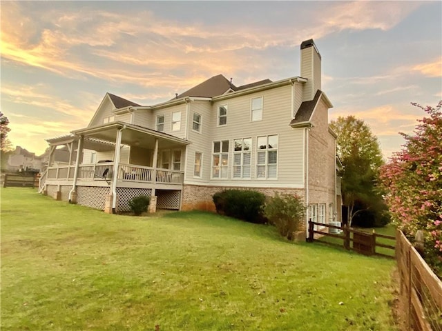 back house at dusk with a pergola, a lawn, and covered porch