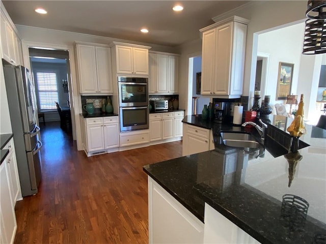 kitchen with dark wood-type flooring, appliances with stainless steel finishes, sink, and white cabinets