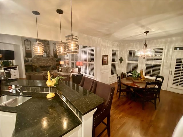 kitchen with sink, a breakfast bar area, a fireplace, and decorative light fixtures