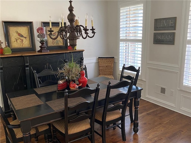 dining room with dark wood-type flooring and an inviting chandelier