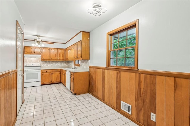 kitchen featuring under cabinet range hood, wainscoting, white appliances, and visible vents